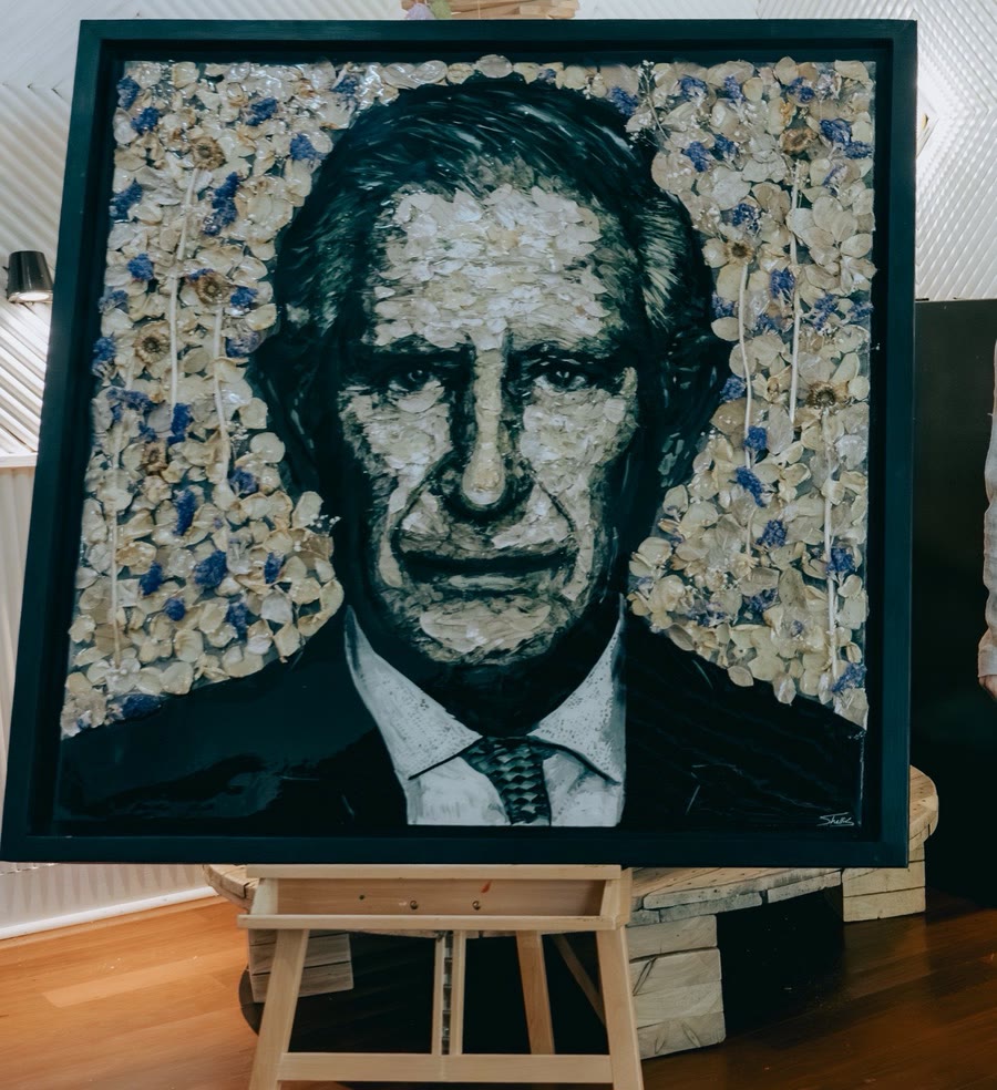 The King of Sustainability portrait: a likeness of HM King Charles III made from pressed flowers, coffee-tinted petals and reclaimed materials, on a dark frame